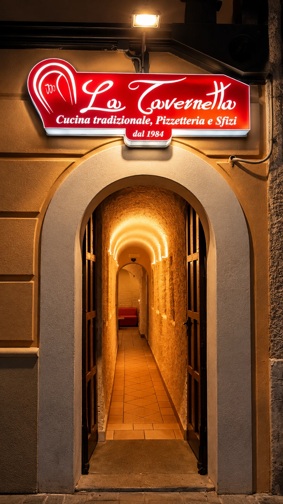 Ingresso di sera de La Tavernetta, con l'insegna illuminata